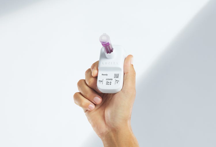 Hand holding up LUCIRA® by Pfizer COVID-19 & Flu Test
